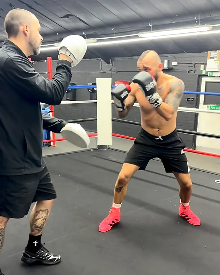Adult coach holding pads for a boxer at Intense Boxing