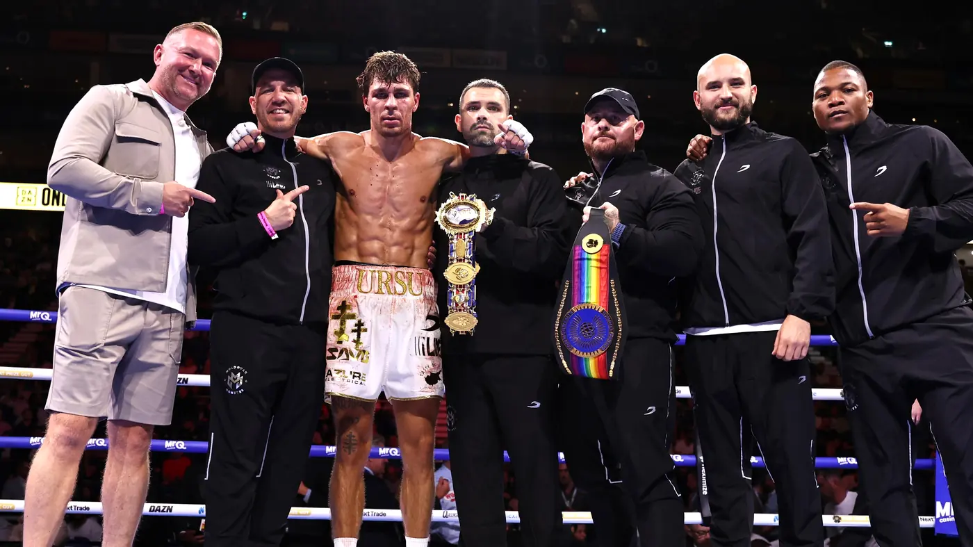 Constantin Ursu in the ring with his British and Commonwealth belts and his team, including coach Marlee Dann